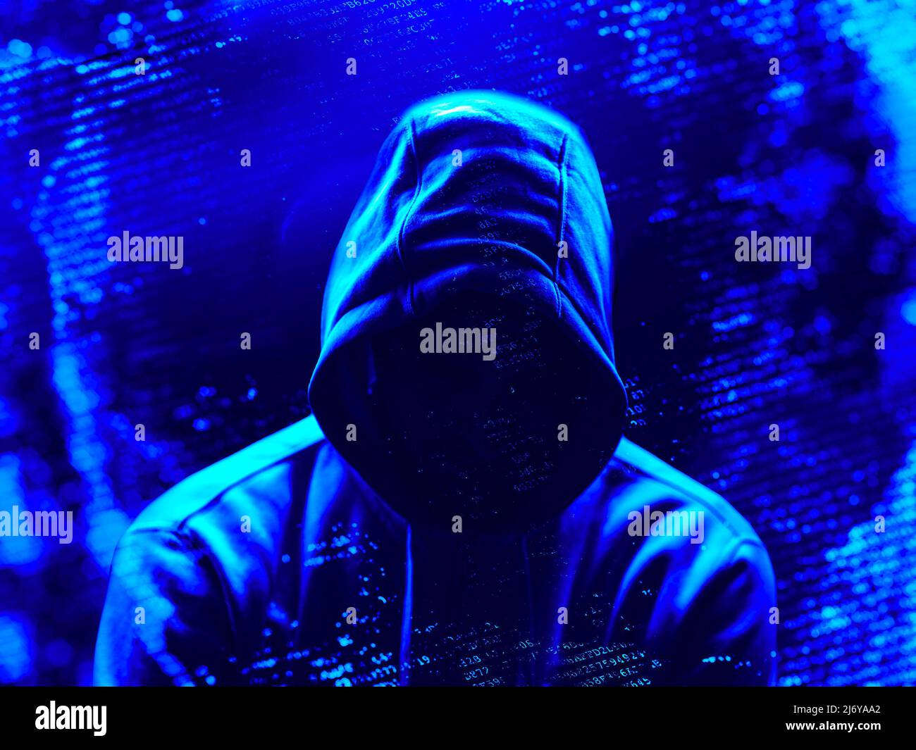A hacker in shadow surrounded by computer code Stock Photo