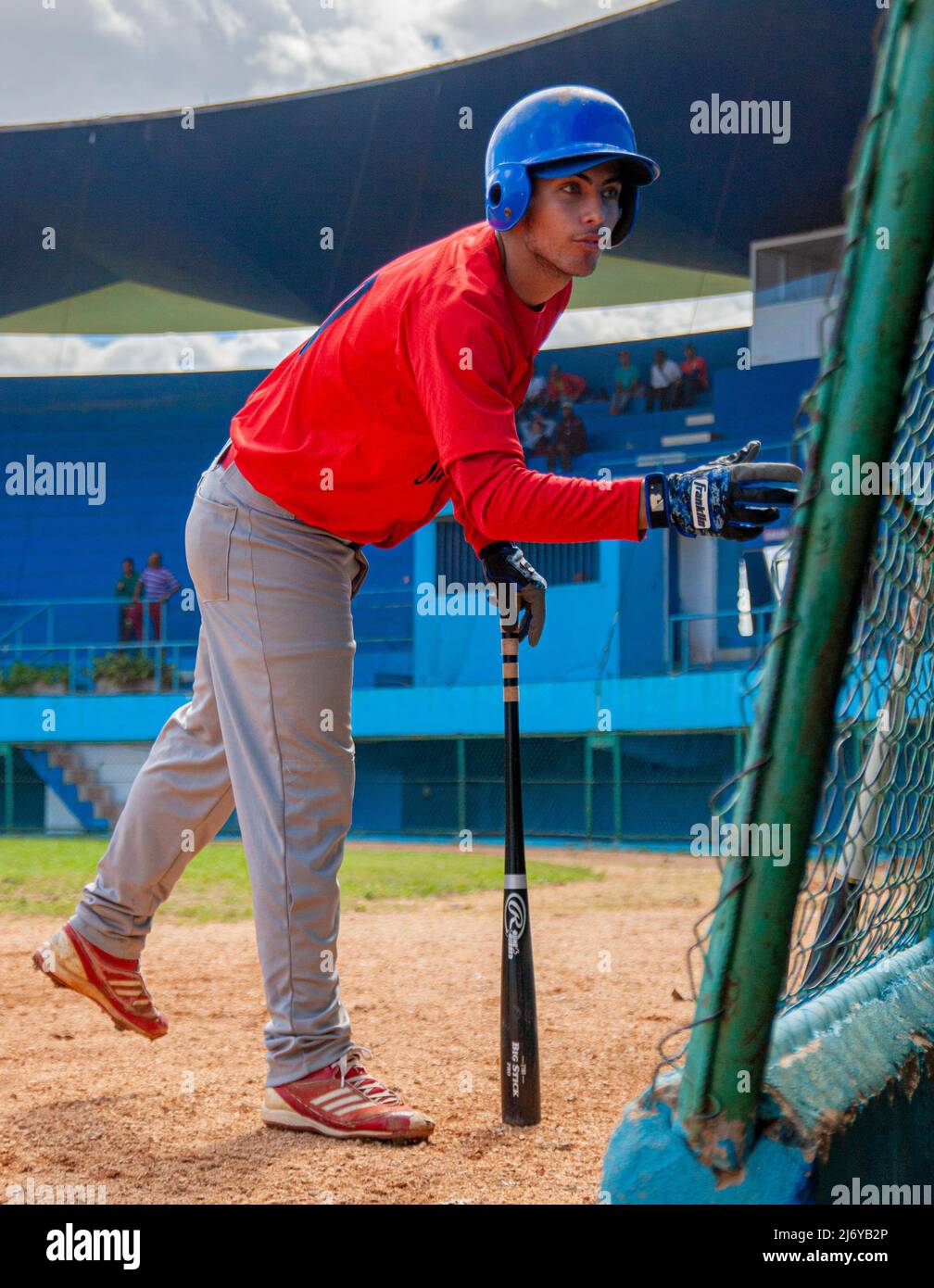 Cuban baseball player on his way to bat talks to a teammate in the dugout at a stadium in Havana, Cuba. Stock Photo