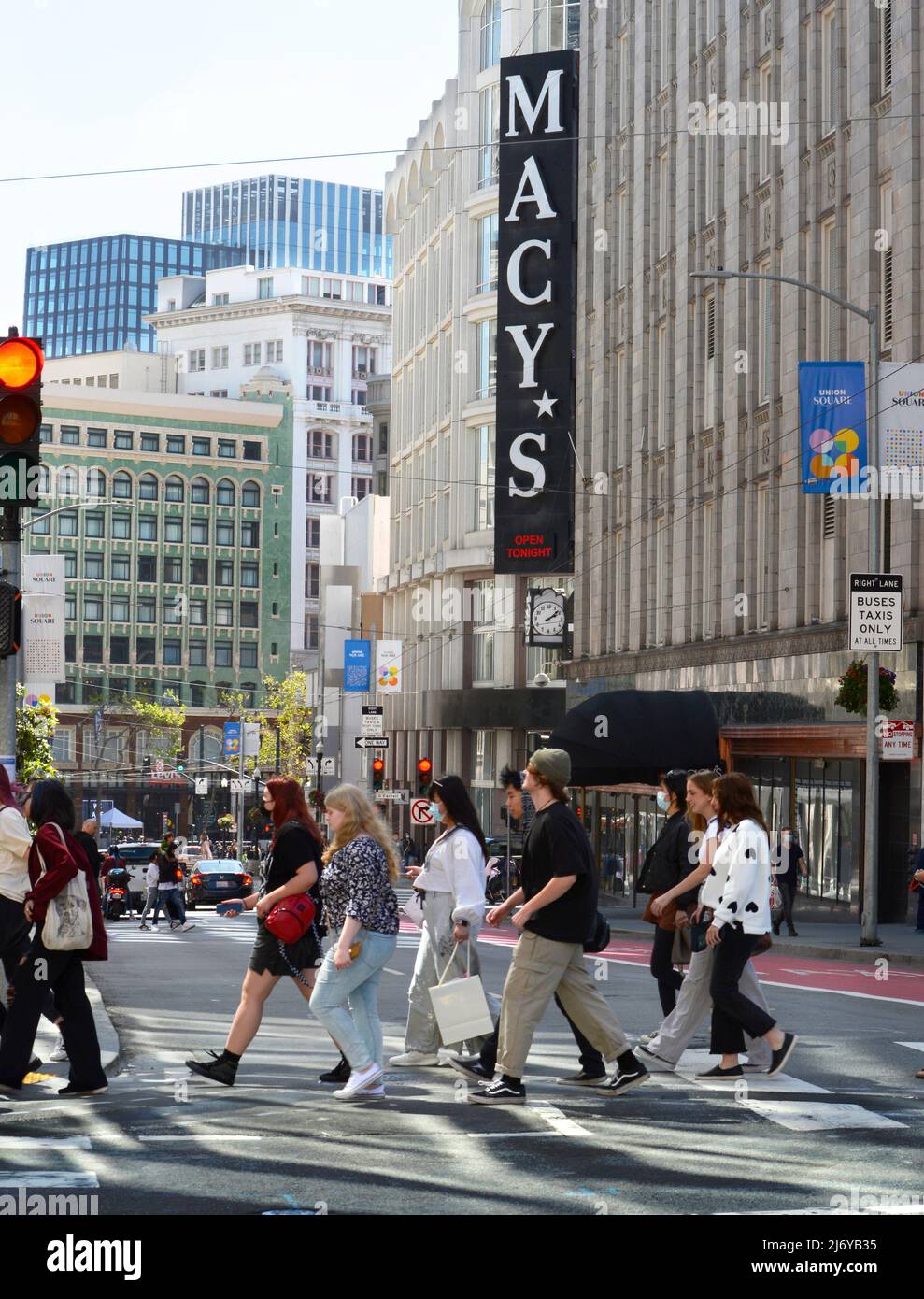 Pedestrians cross a downtown street near Macy's Department Store in