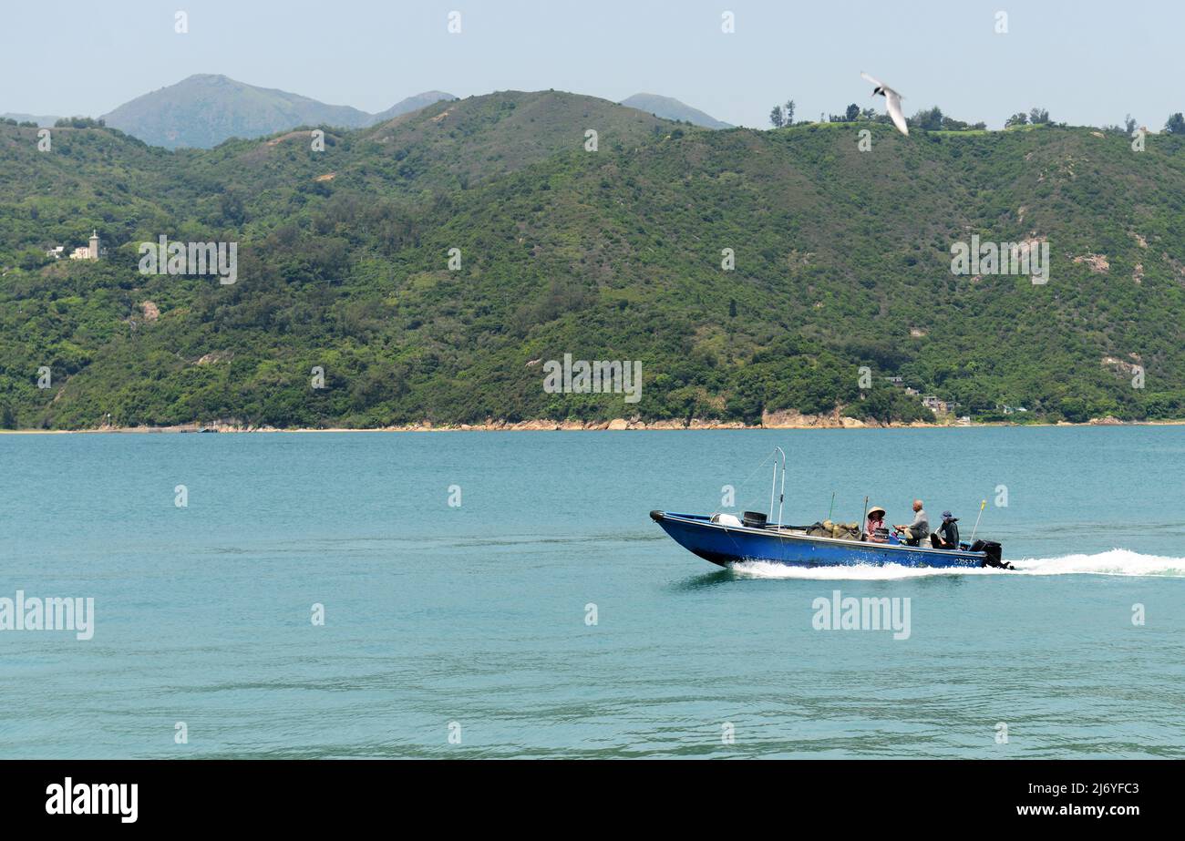 Fishermen in a speedboat of the coast of Lantau island in Hong Kong. Stock Photo