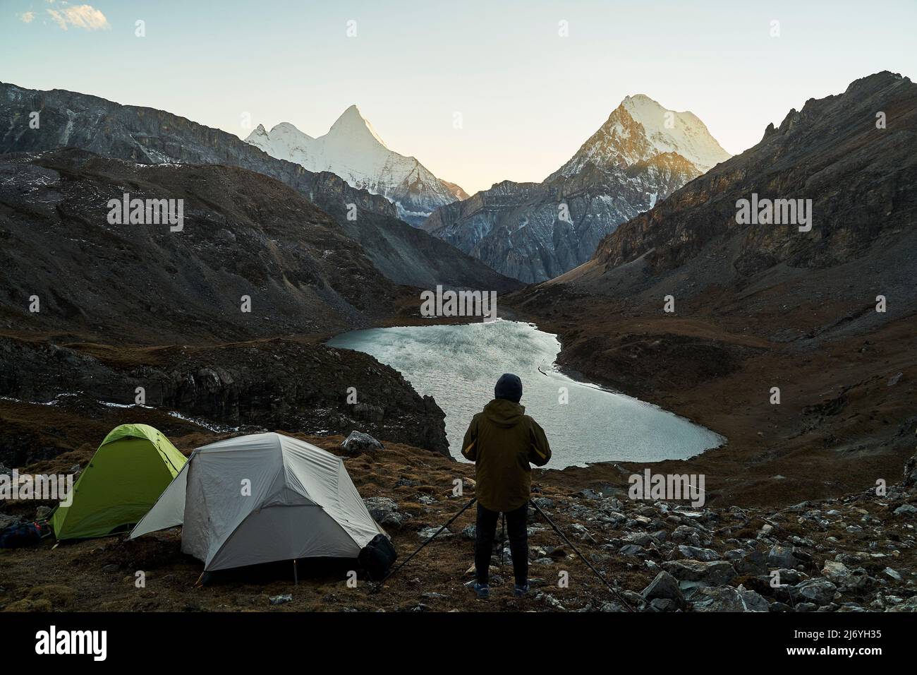 asian camper photographer taking a picture of mountain and lake in yading national park, daocheng county, sichuan province, china Stock Photo