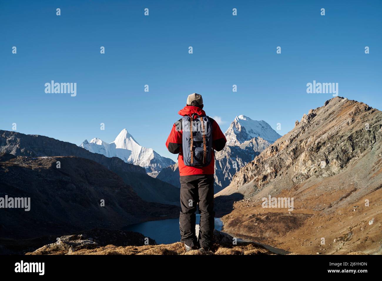 rear view of asian man backpacker male hiker looking at mountains in yading national park, daocheng county, sichuan province, china Stock Photo