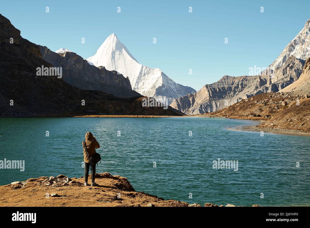 rear view of an asian photographer taking a photo of the holy mount jampayang and lake boyongcuo in yading national park, daocheng county, sichuan pro Stock Photo
