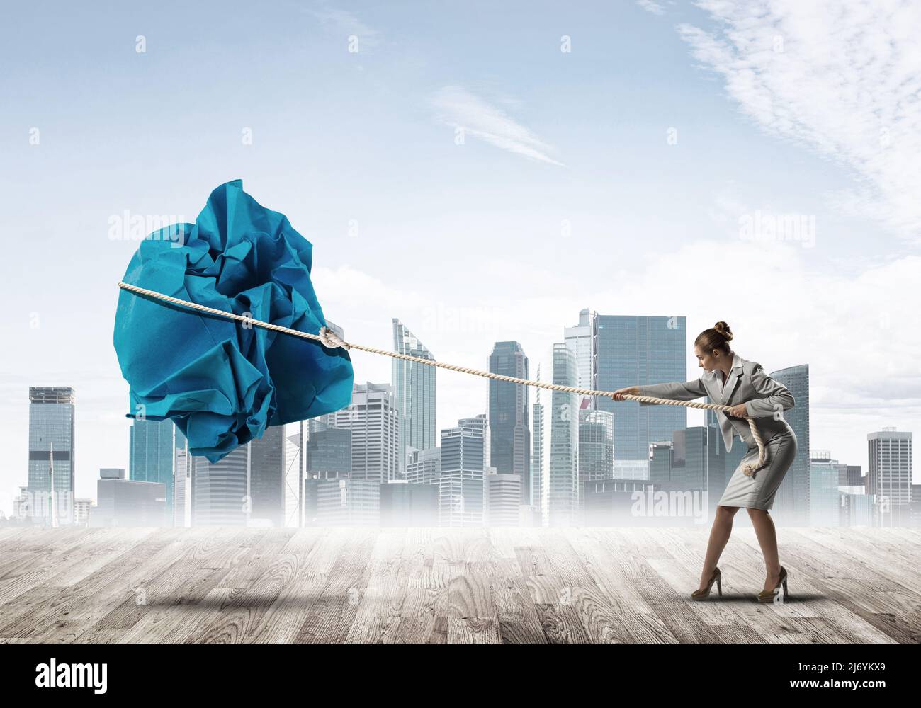 Woman pulling with effort big crumpled ball of paper as creativity sign