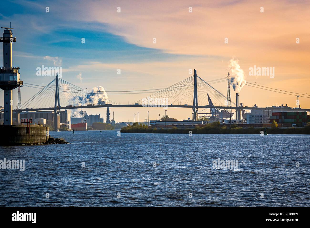 sight over port of hamburg industrial area with hamburgs most famous suspension bridge called Kohlbrand bridge, crossing the elbe river during dusk Stock Photo