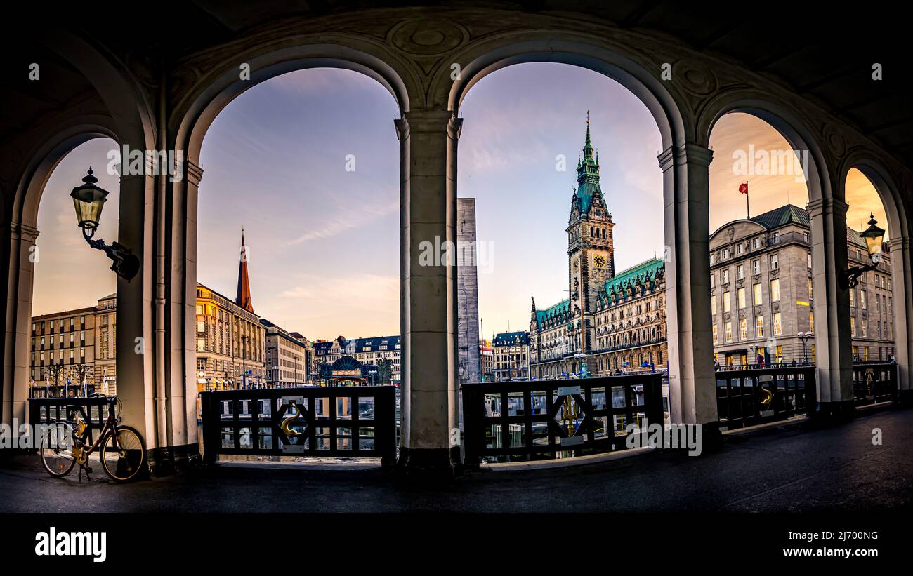 Supernatural ultra wide angle panorama with low angle view from the alsterarkaden over the town square to the famous town hall in downtown district. Stock Photo