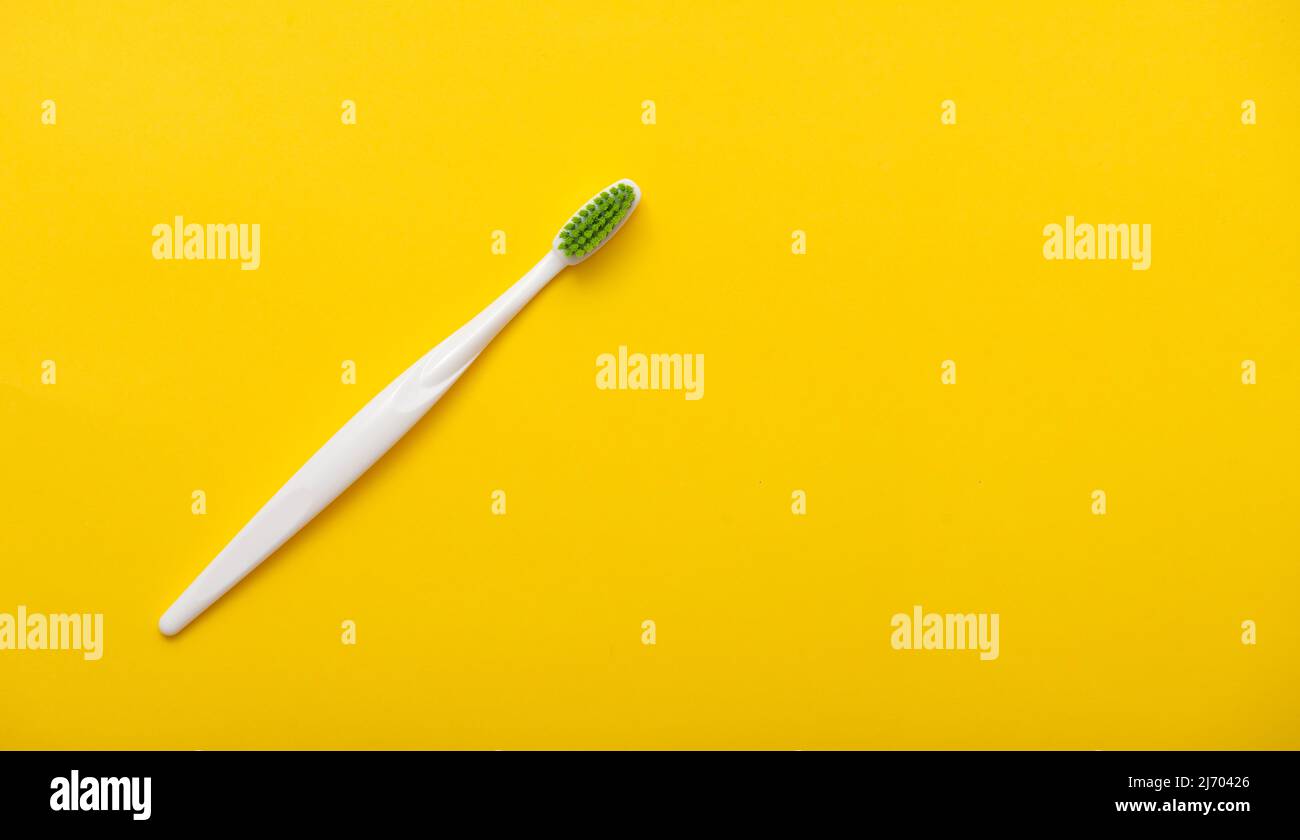 White plastic toothbrush on bright yellow background as flat lay, top ...