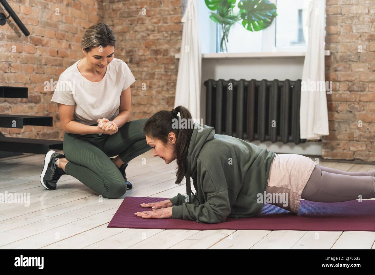 elderly woman during her fitness workout with personal trainer in gym ...