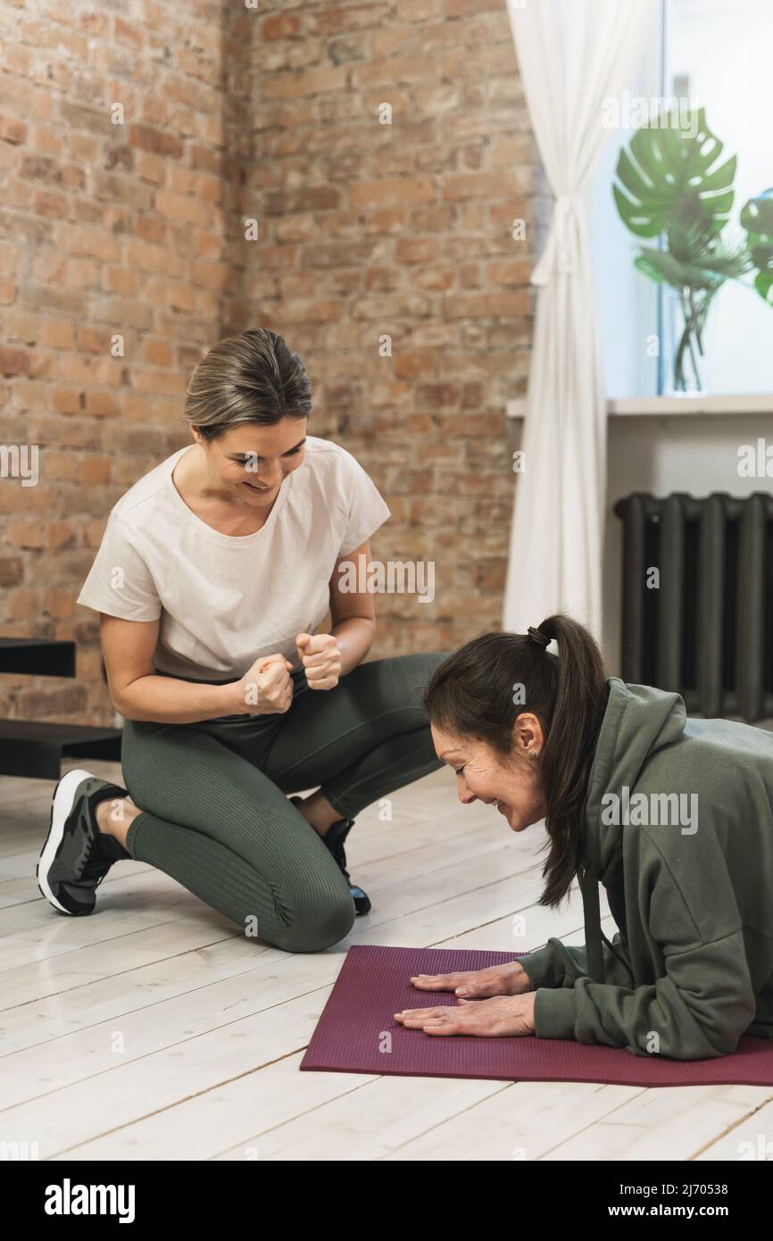 elderly woman during her fitness workout with personal trainer in gym ...
