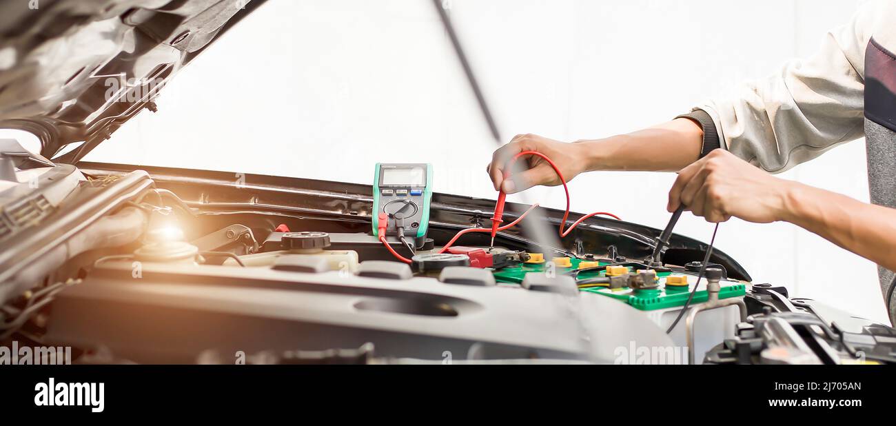 A technician is checking the car battery for availability.; Stock Photo