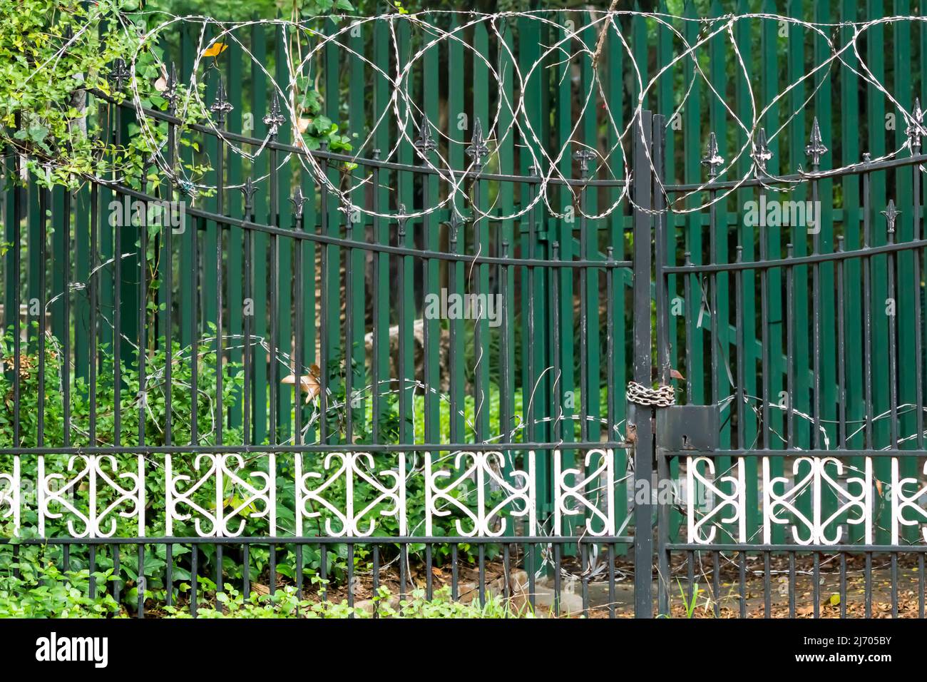 closeup of security fence and padlocked metal gates with razor wire on top concept safety and security Stock Photo