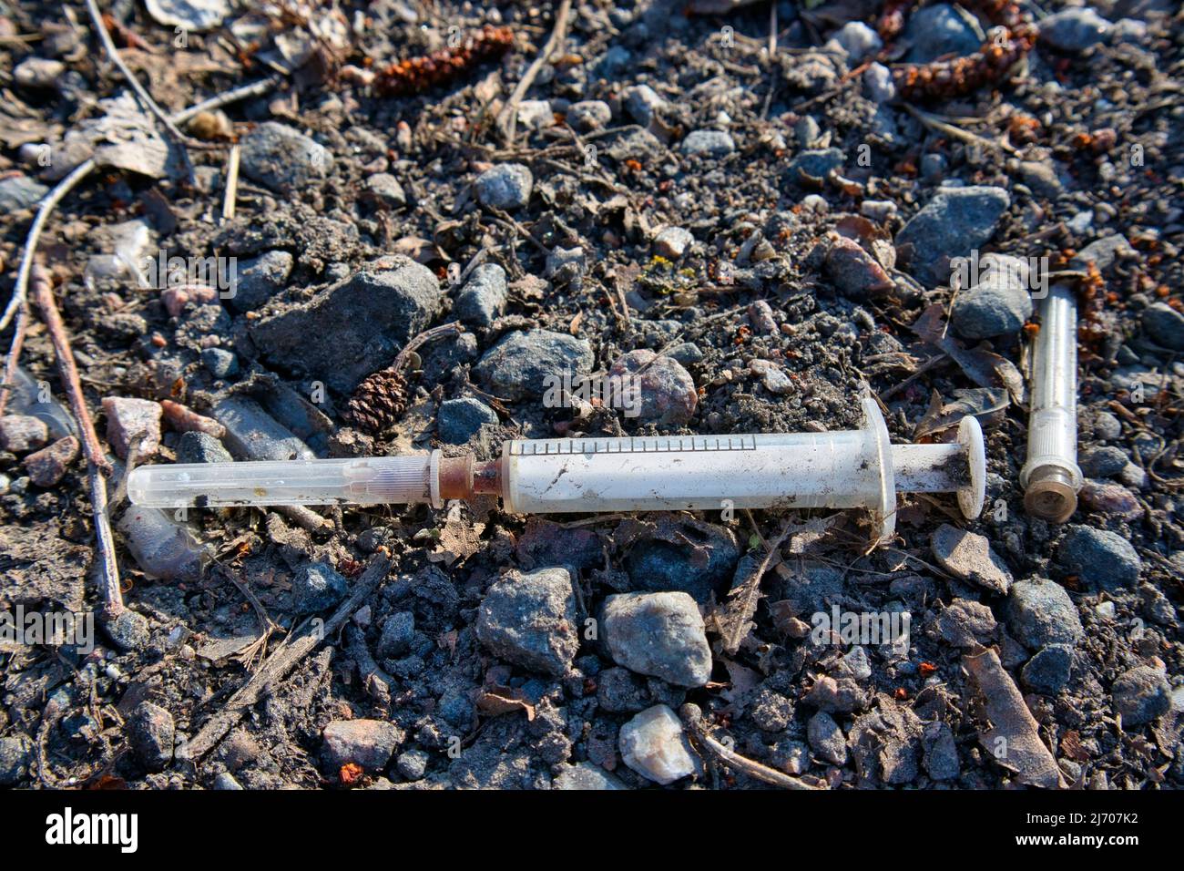 Used drug syringe on the ground Stock Photo