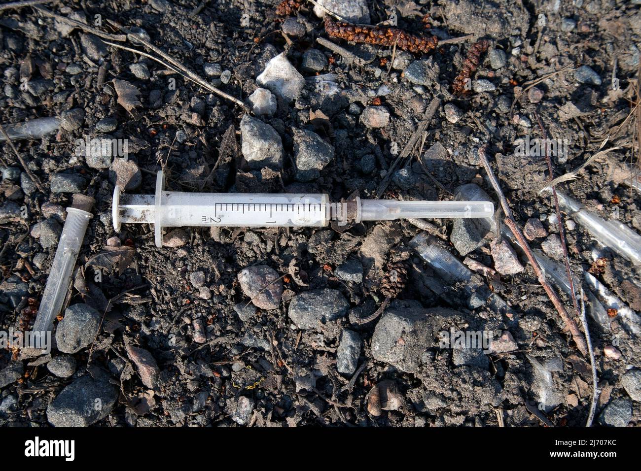 Used drug syringe on the ground Stock Photo