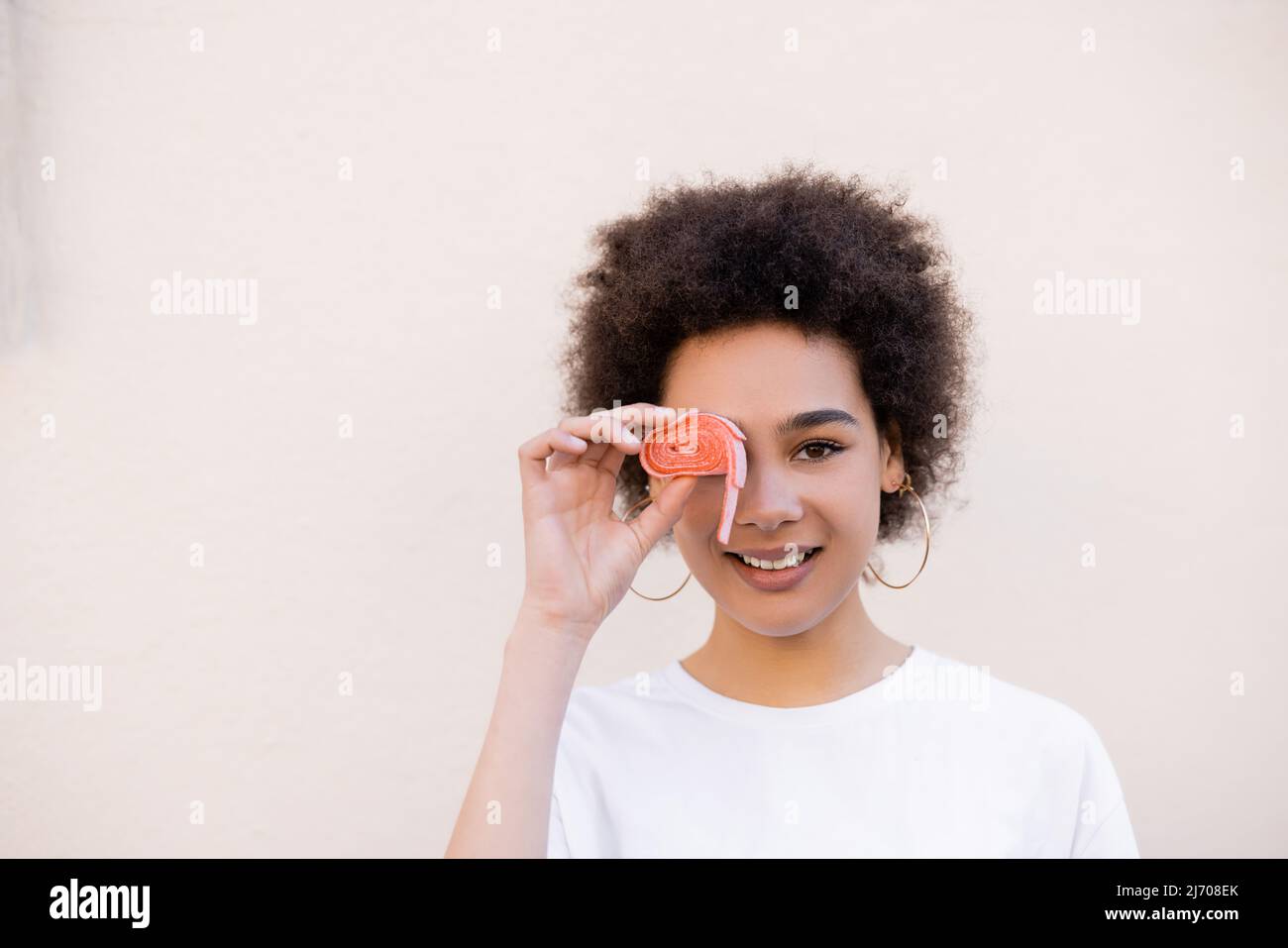 pleased young african american woman covering eye with jelly bubble