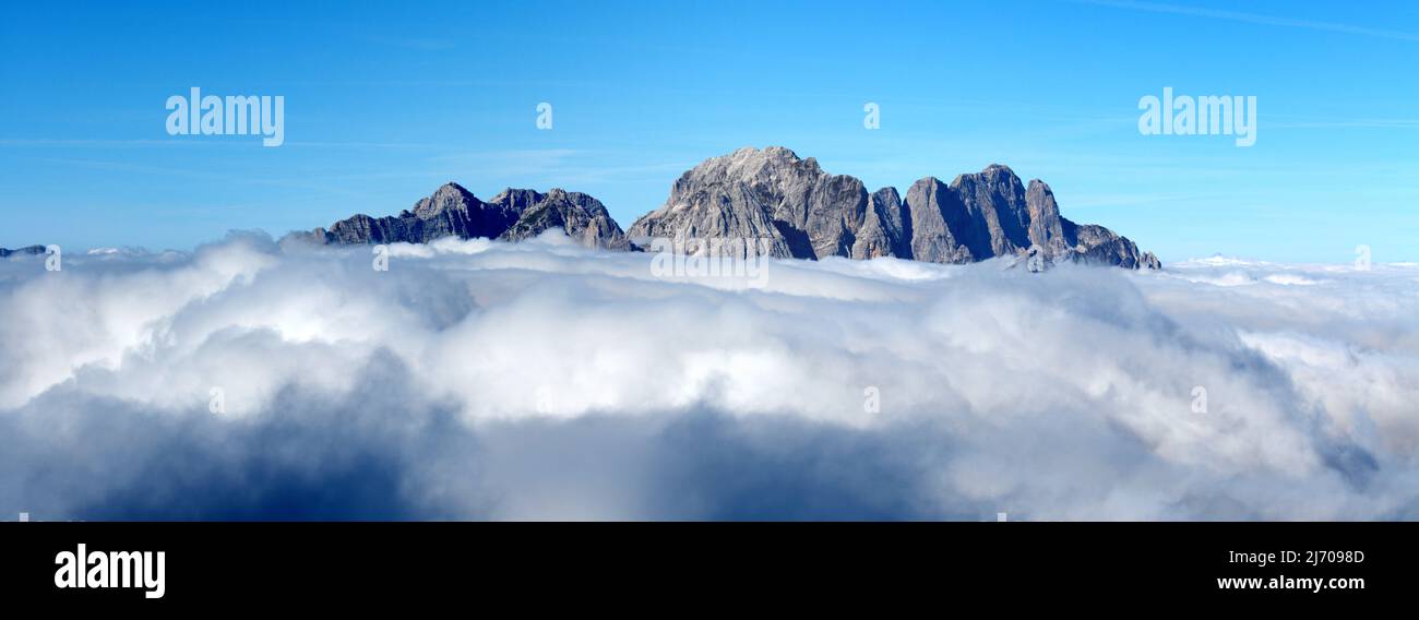 Mangart mountain in clouds, Julian Alps, Slovenia. Morning mists and fog around Mangart rocky mountain peak Stock Photo