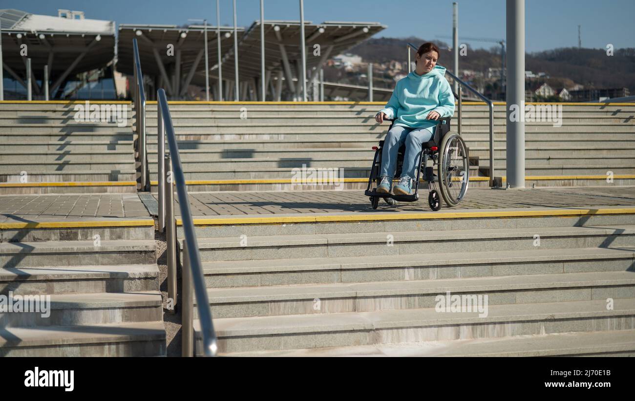 A caucasian woman in a wheelchair cannot go down stairs without a ramp