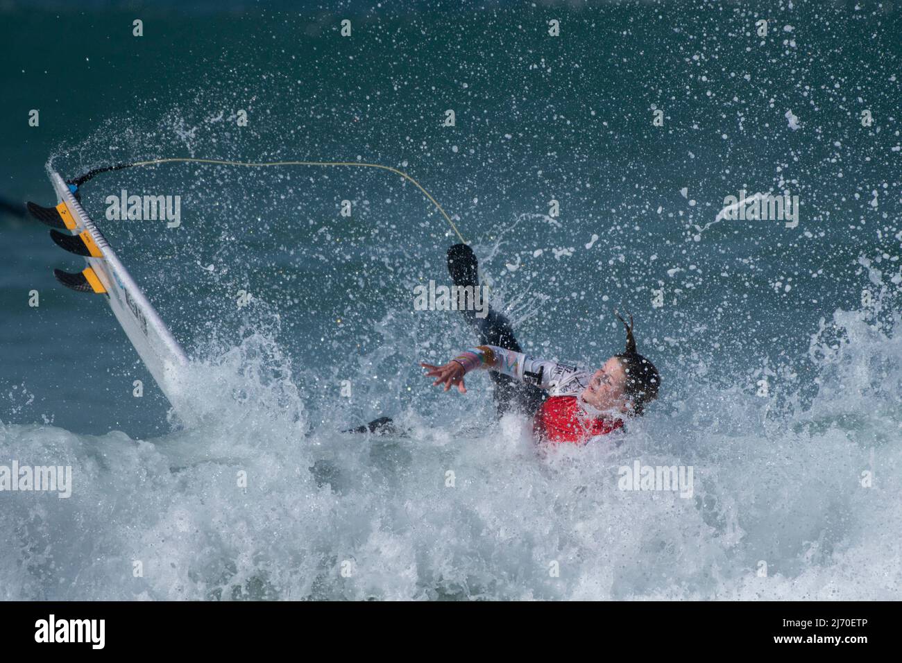 A female surfer wiping out competing in a surfing competition at Fistral in Newquay in Cornwall in the UK Stock Photo