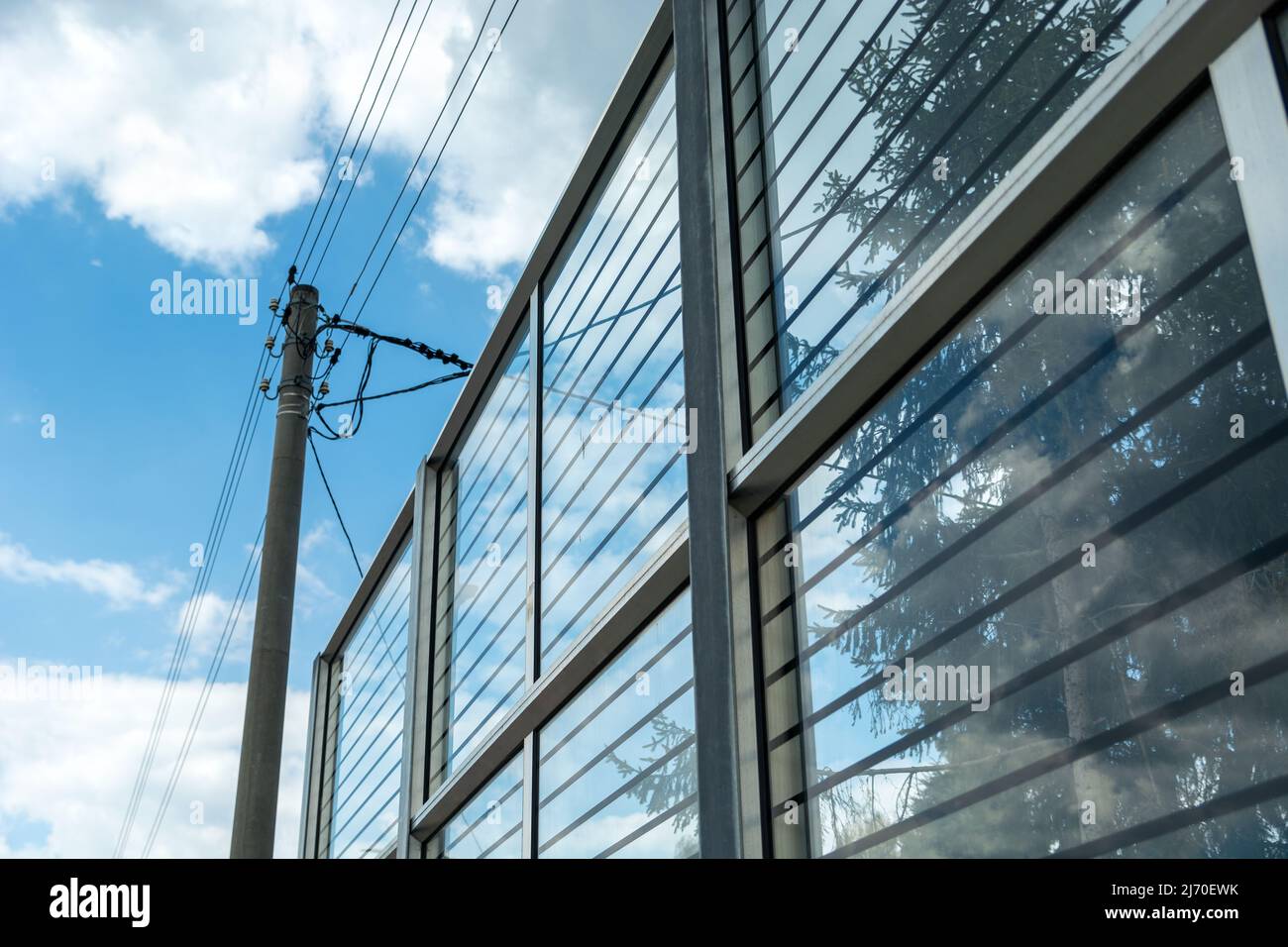 Electric pole standing by glass noise barriers Stock Photo