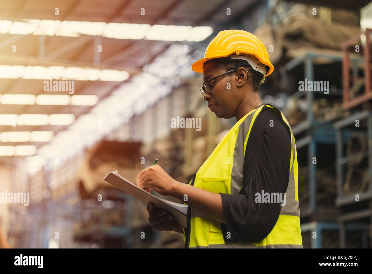 Engineer black women worker, Professional woman afican mechanical maintenance work in factory checking stock inventory in warehouse. Stock Photo