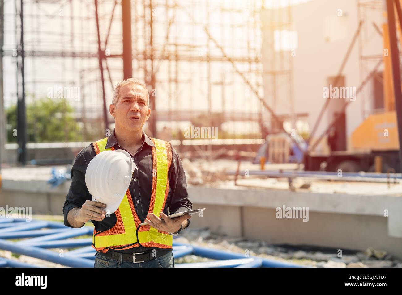 Tired fatigued engineer worker constructor working in construction site. Stock Photo
