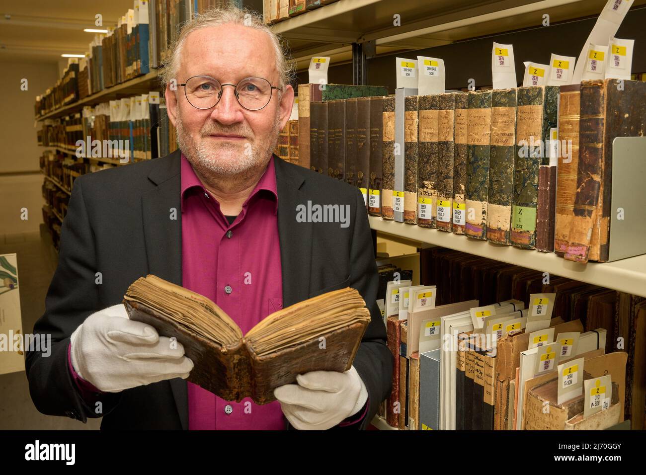 04 May 2022, Rhineland-Palatinate, Koblenz: Armin Schlechter, head of the Collections Department of the Landesbibliothekszentrum, holds the purchased parchment manuscript with the title 'Libellus antiquarum definitionum' in his hands. The booklet of an abbot with 124 leaves in the format 7.2 by 13 centimeters in a brown leather binding was certainly created in the medieval writing workshop in the monastery Himmerod in the Eifel.(To dpa: Valuable monastery manuscript returns after about 700 years). Photo: Thomas Frey/dpa Stock Photo