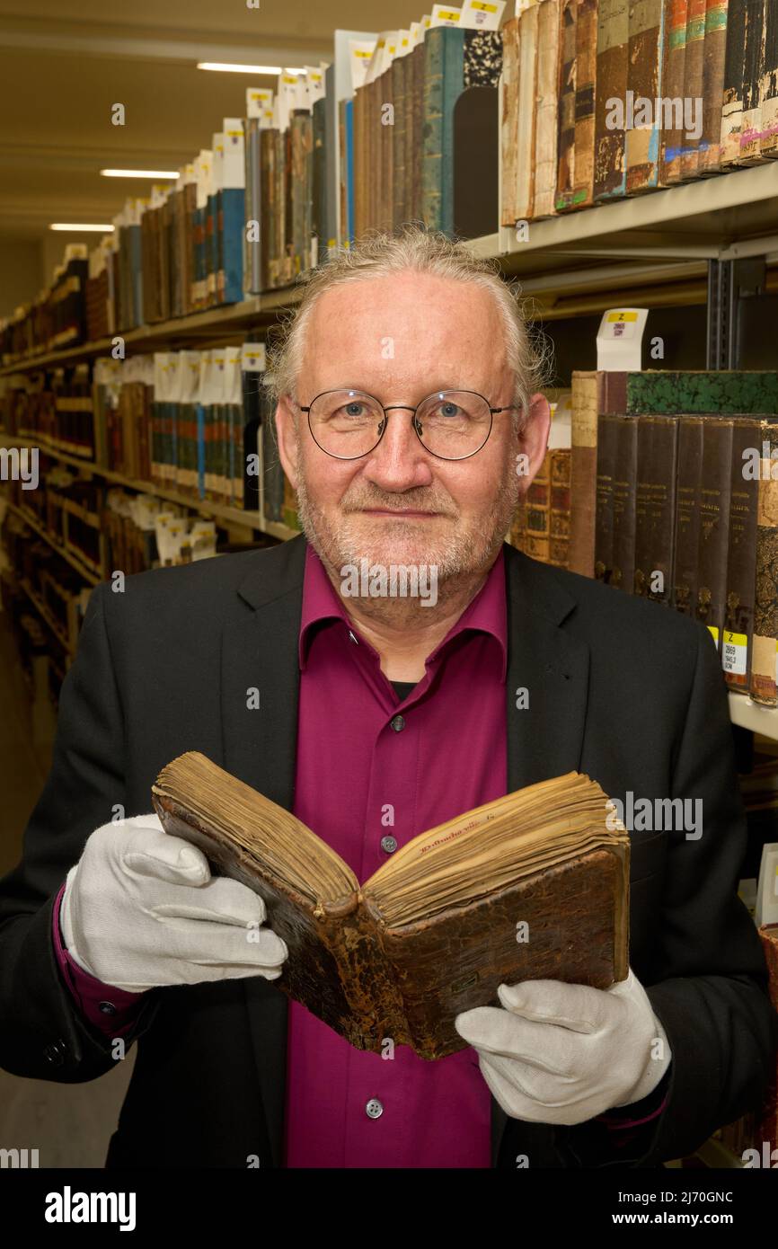 04 May 2022, Rhineland-Palatinate, Koblenz: Armin Schlechter, head of the Collections Department of the Landesbibliothekszentrum, holds the purchased parchment manuscript entitled 'Libellus antiquarum definitionum' in his hands. The booklet of an abbot with 124 leaves in the format 7.2 by 13 centimeters in a brown leather binding was certainly created in the medieval writing workshop in the monastery Himmerod in the Eifel.(To dpa: Valuable monastery manuscript returns after about 700 years). Photo: Thomas Frey/dpa Stock Photo