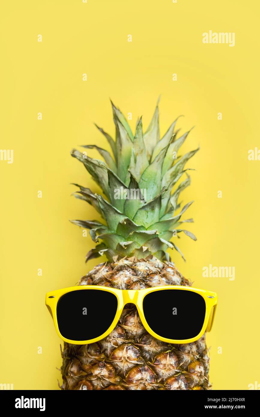 Summertime concept. Pineapple with yellow sunglasses and space for text over yellow background Stock Photo
