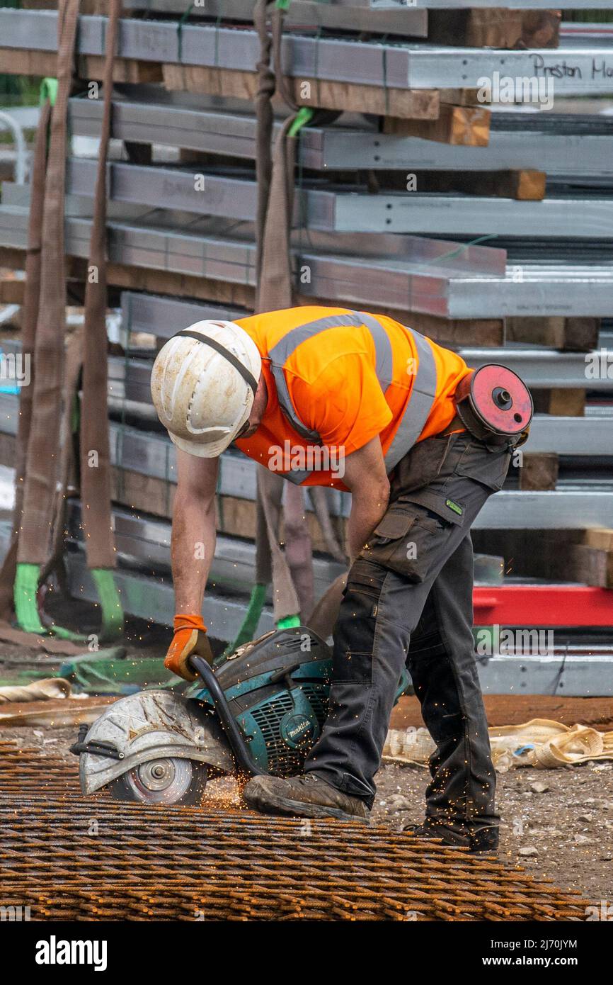 Technik Concrete Pumping; Using a circular saw to cut steel mesh in Preston, UK Stock Photo