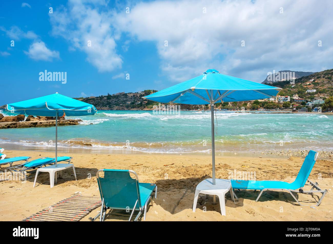 Sun loungers and parasols on empty beach at windy day. Almyrida. Crete, Greece Stock Photo