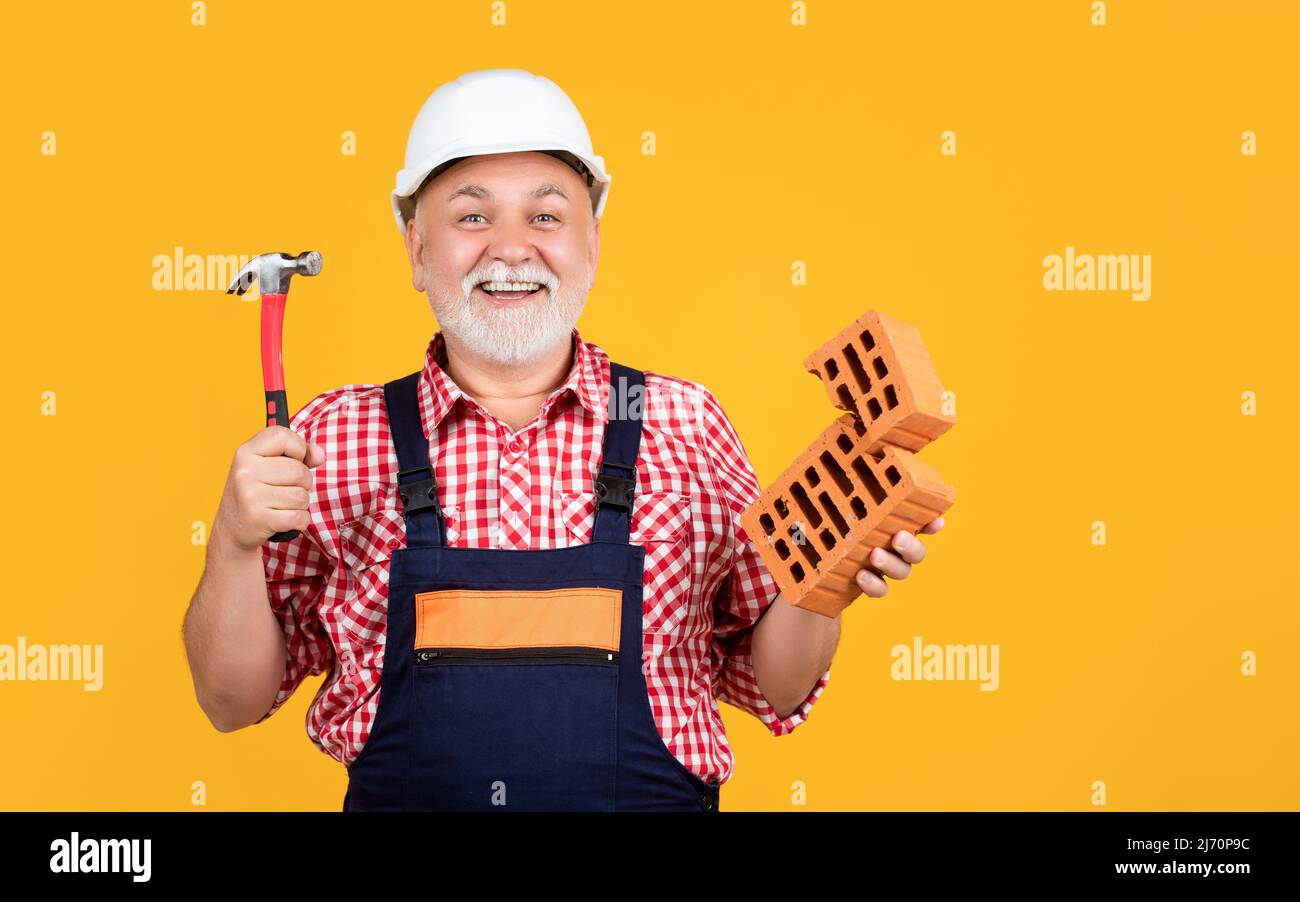 happy mature man worker in helmet on yellow background Stock Photo