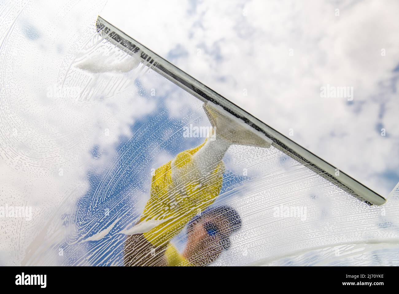 Window cleaner using a squeegee to wash a window Stock Photo Alamy