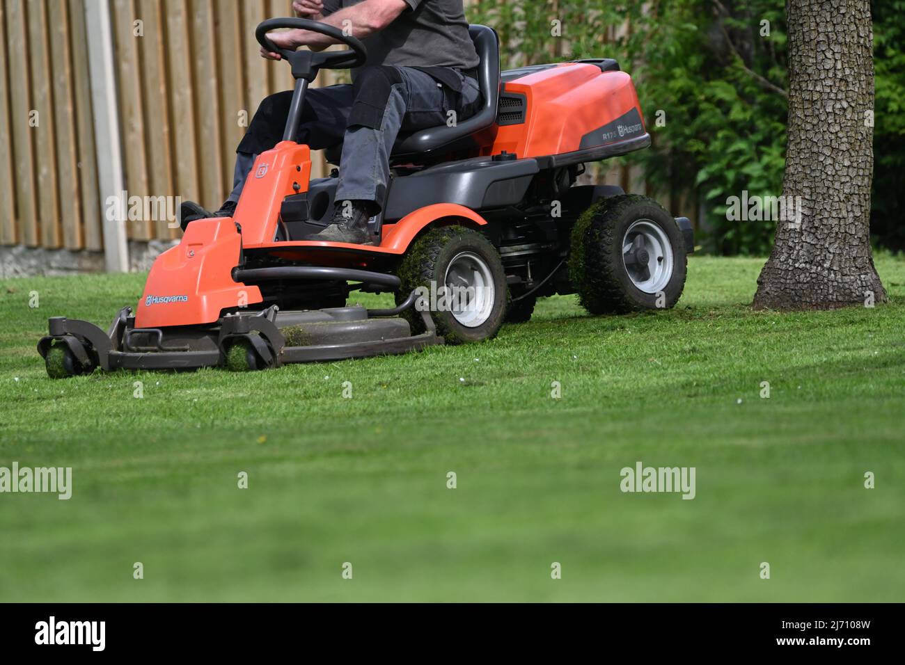 A man mowing a lawn on a ride on mower on a spring day Stock Photo