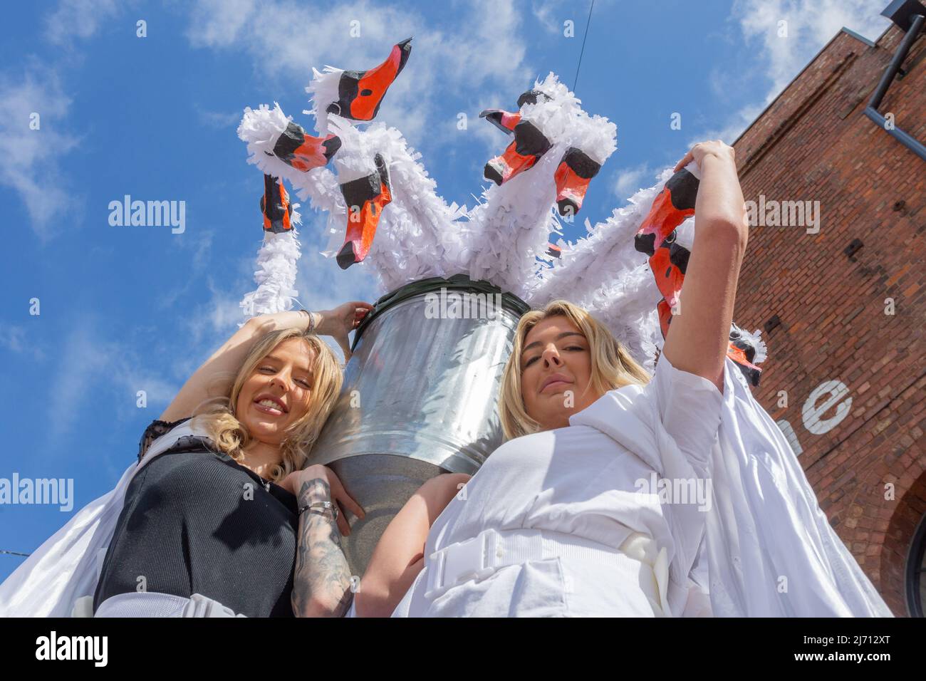 Coventry, UK. 5th May, 2022.  Performers Courteney Gaskin and Katie Jones of Imagineer events company hold puppet swans aloft as they prepare for The Queen's Favourites - a part of the The Queen's Platinum Jubilee Pageant next month.  The performers are highlighting the quirky annual ceremony of Swan Upping, the census of the swan population on the River ThamesCredit: Peter Lopeman/Alamy Live News Stock Photo