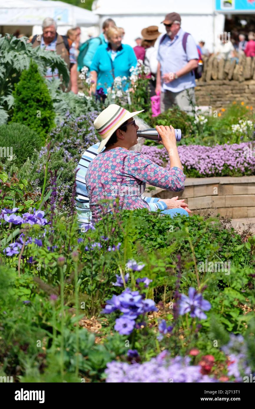 Malvern, Worcestershire, UK – Thursday 5th May 2022 – Visitors enjoy the warm sunny weather and a chance to sit and rest in the new Platinum Jubilee Garden on the opening day of the 35th RHS Malvern Spring Festival of gardening and plants. The show features six show gardens and a Platinum Jubilee Garden. Photo Steven May / Alamy Live News Stock Photo
