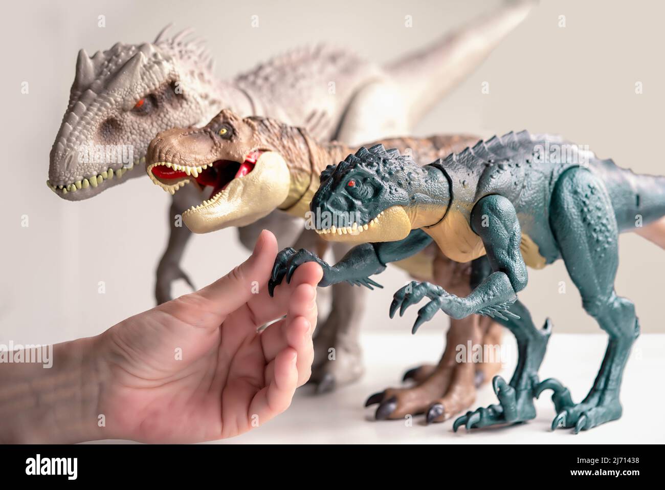 Handshake with dinosaurs. Hand touches dinosaur toys. Stock Photo