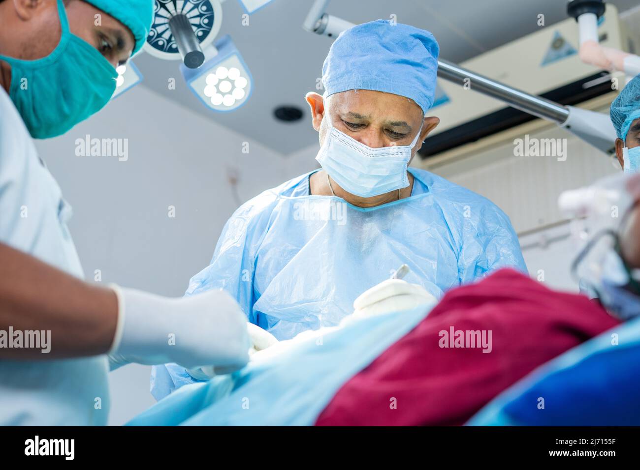 concentrated surgeon busy performing surgery to sick patient at operation theater - concept of expertise, specialist and profesional treatment Stock Photo