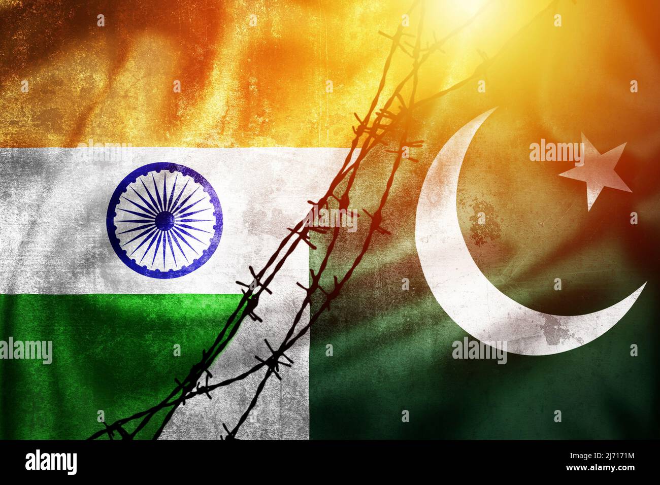 Grunge flags of India and Pakistan divided by barb wire sun haze illustration, concept of tense relations between India and Pakistan Stock Photo