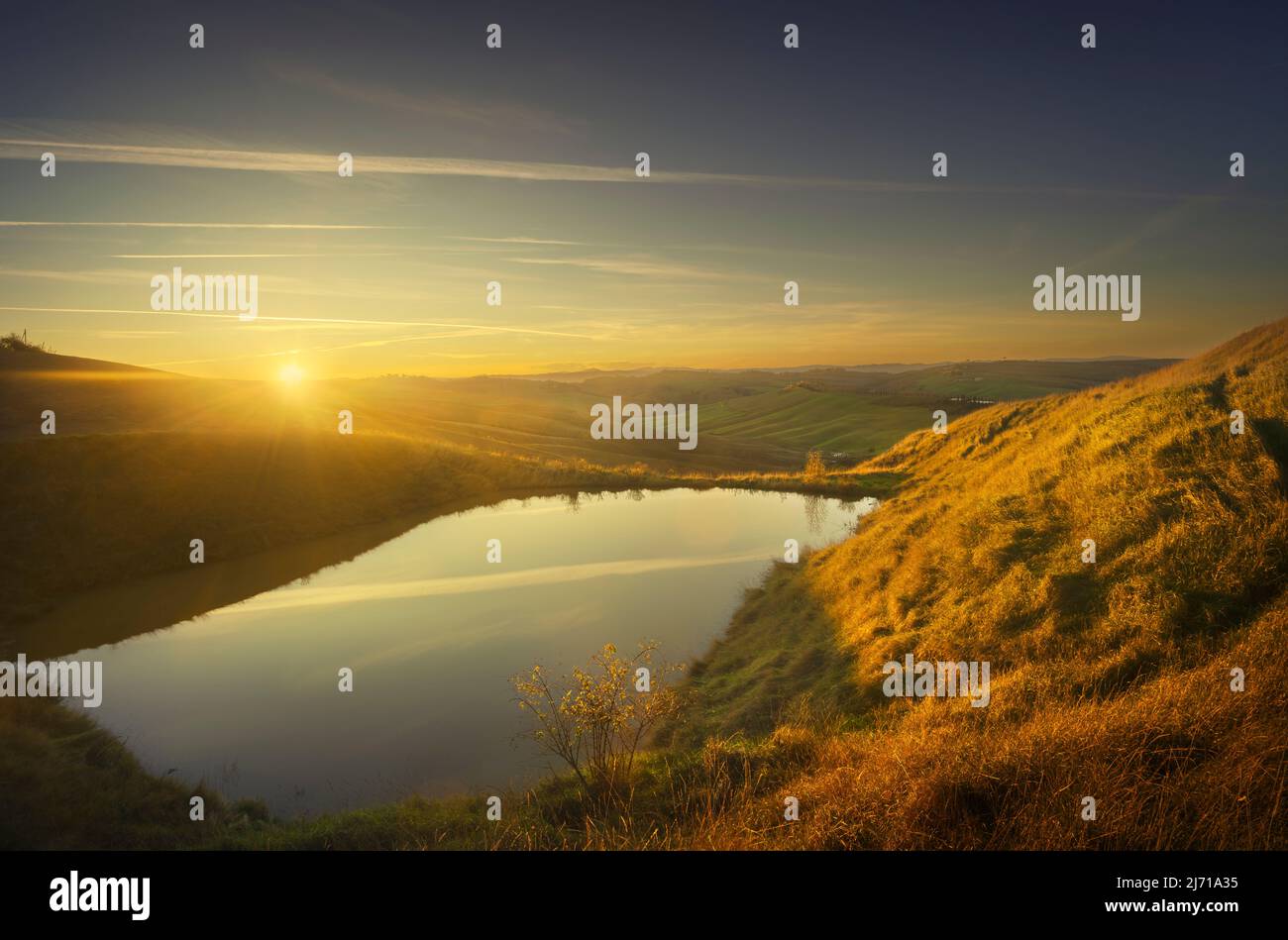 Small lake and rolling hills at sunset. Landscape in Crete Senesi, Asciano, Tuscany, Italy Stock Photo