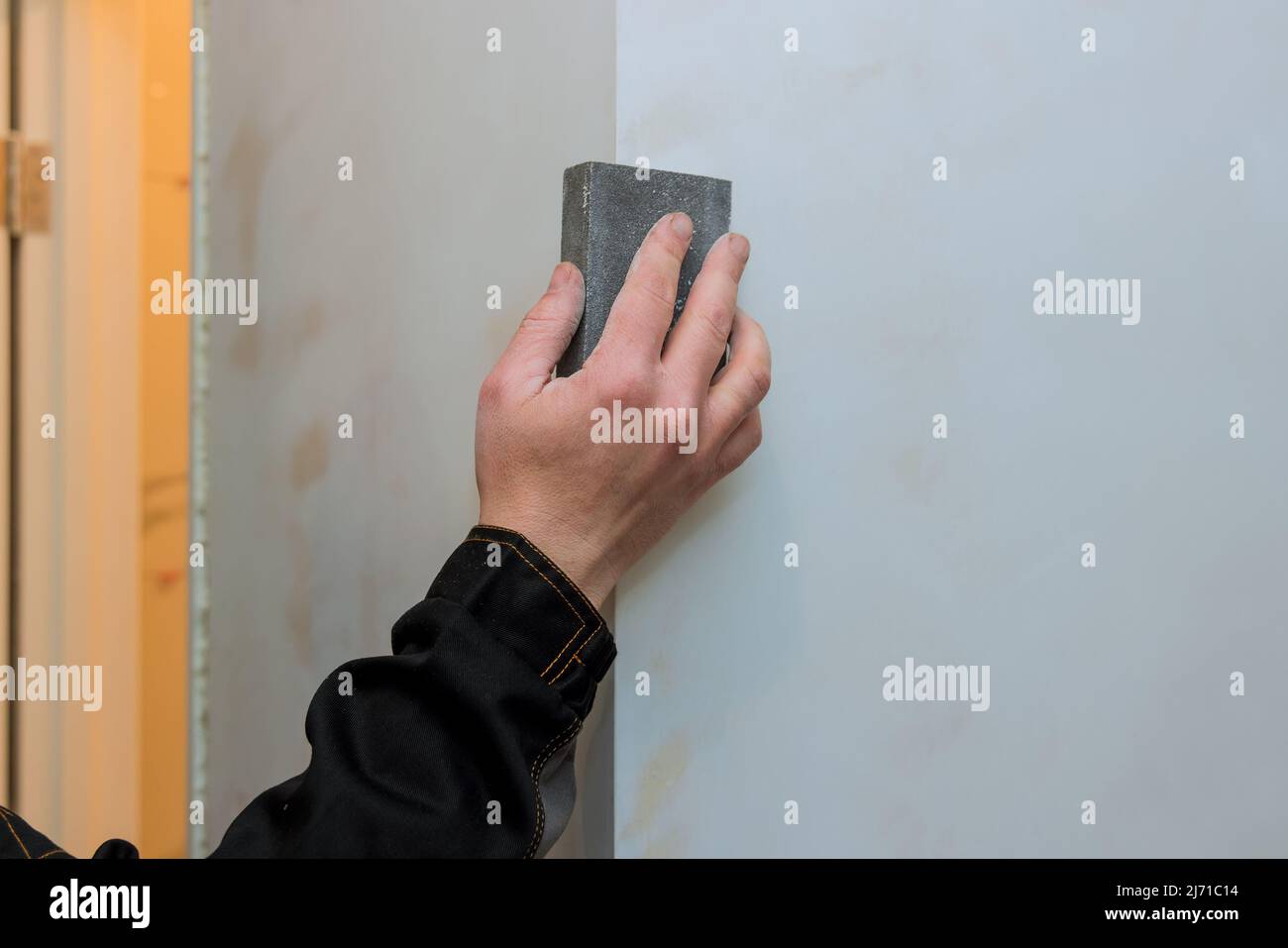 Worker sanding the drywall mud using sand trowel during renovation the house Stock Photo