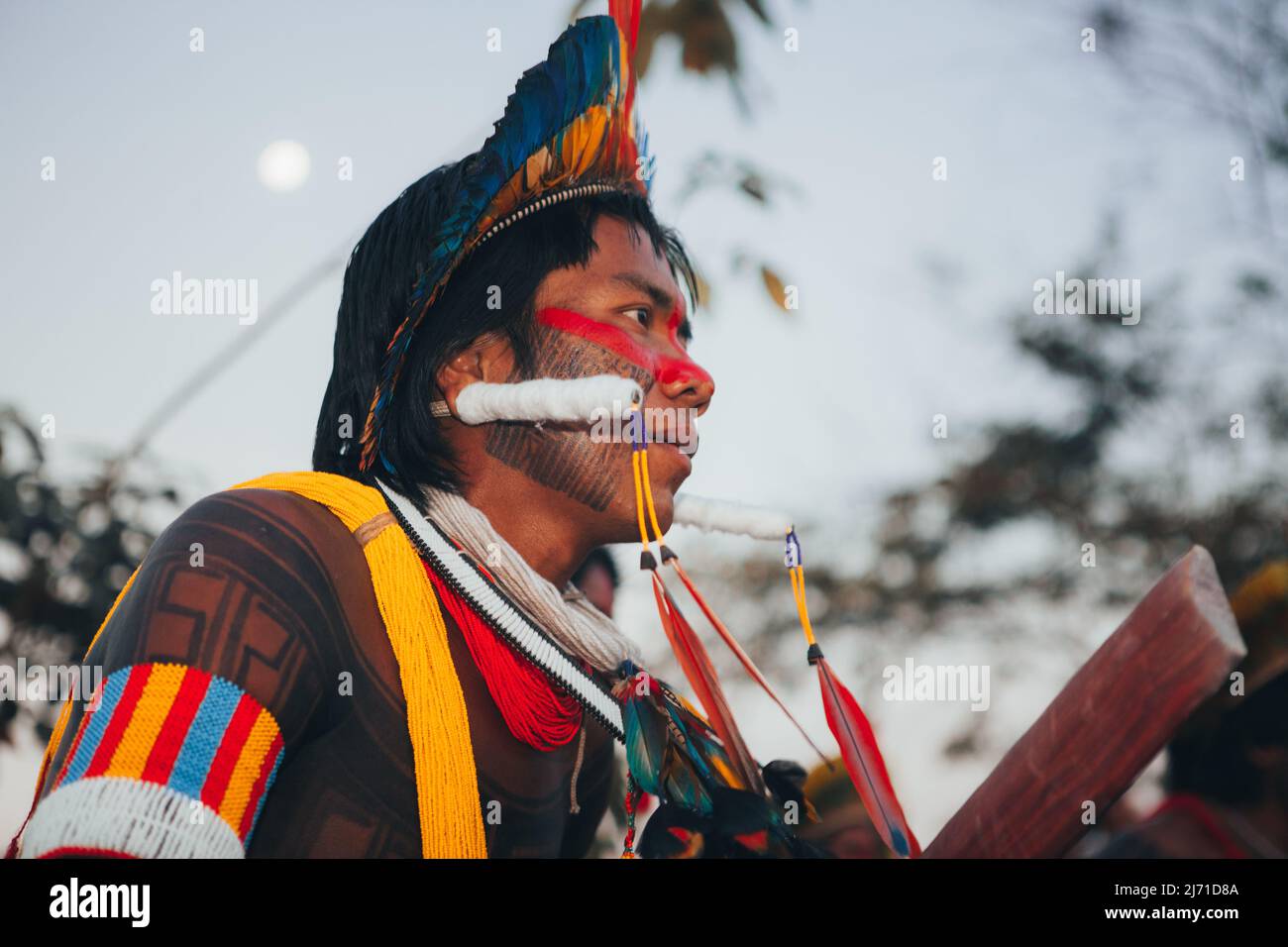 Indigenous man from a Brazilian Amazon tribe wearing feather headdress known as cocar and tribal body art. Xingu River, Amazon, Brazil. 2009. Stock Photo