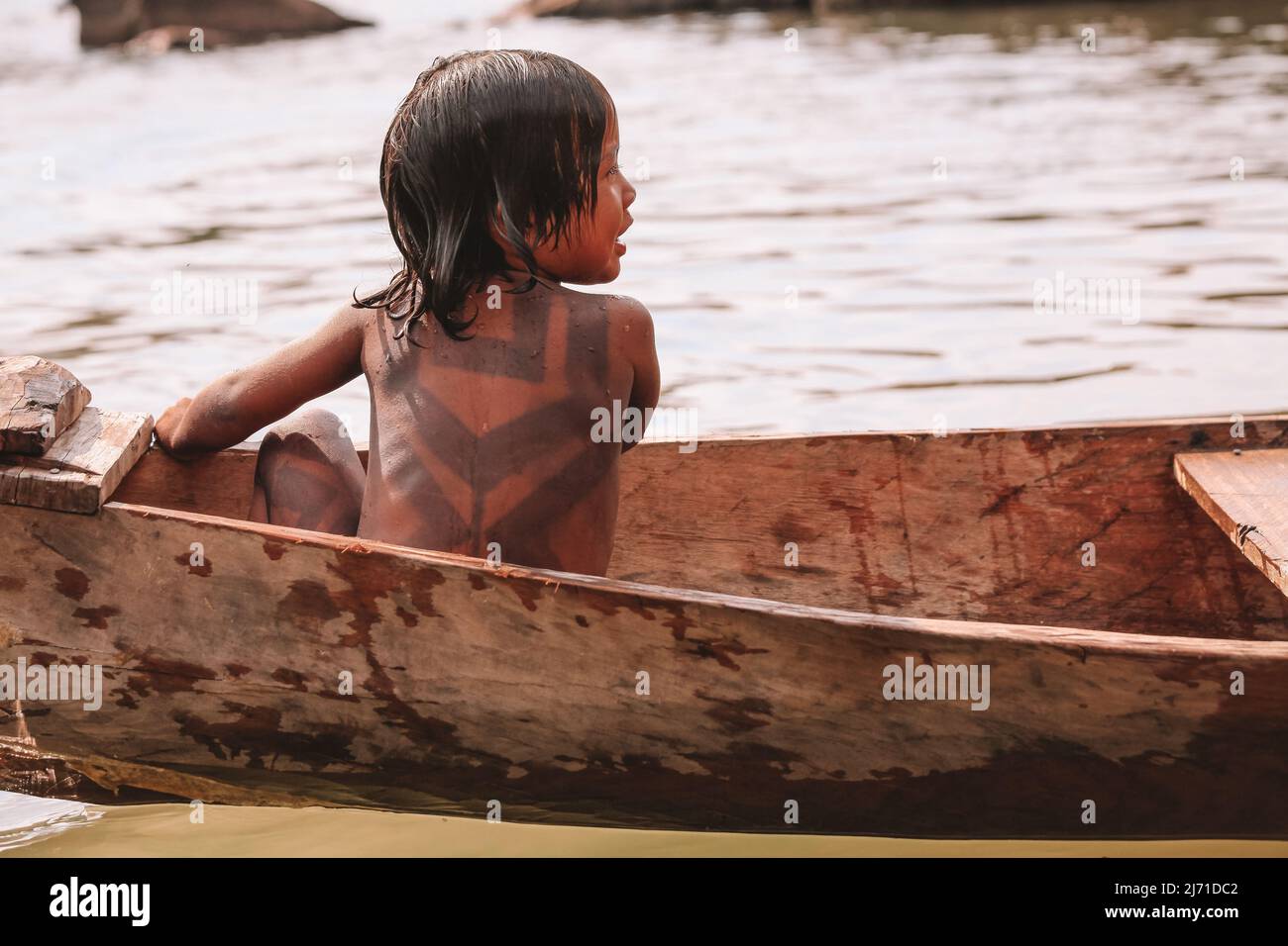Indian child from the Asurini tribe in Brazil, playing inside a canoe in the Amazon River. 2010. Stock Photo