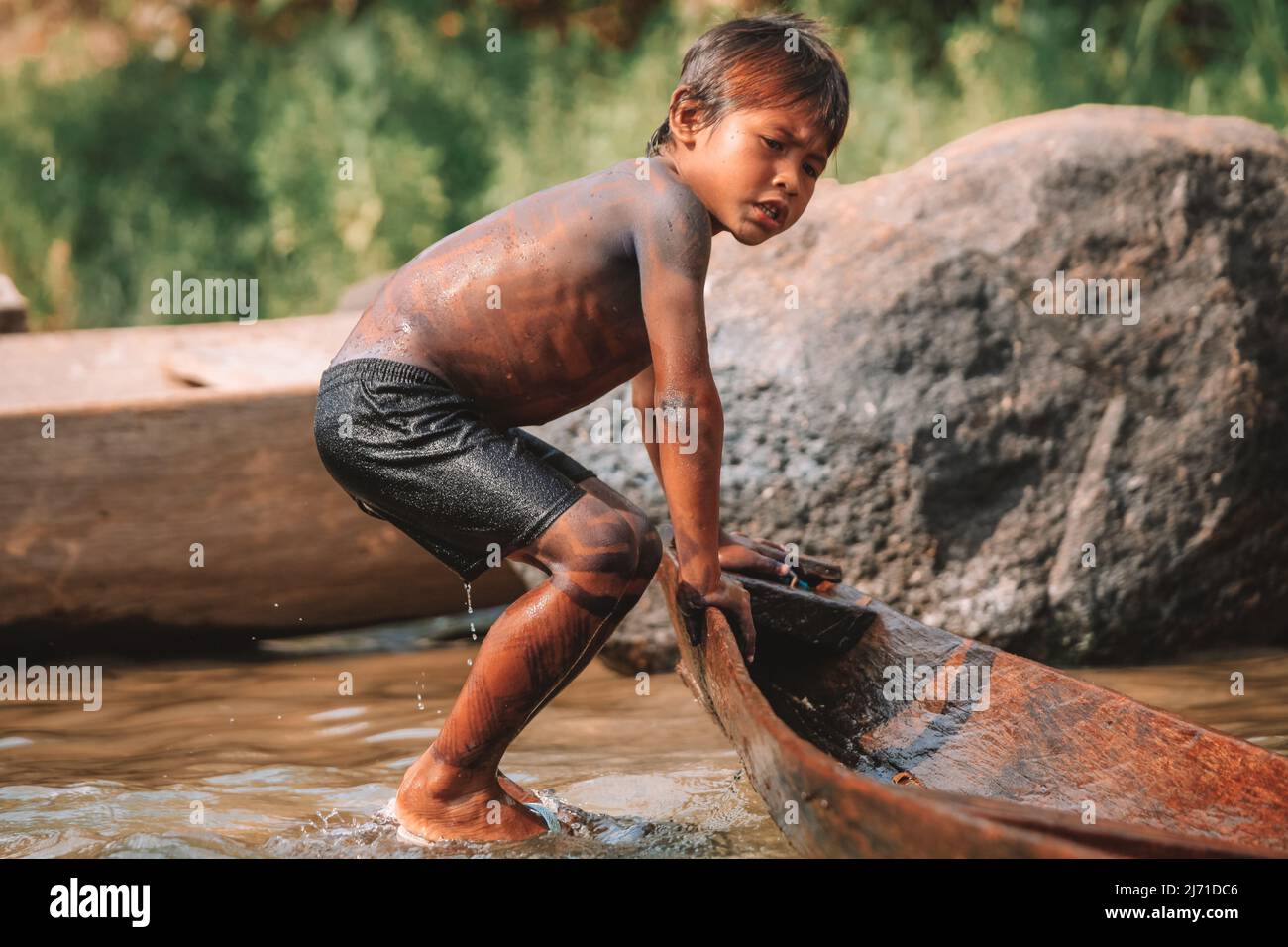 Indigenous boy dragging a canoe to the Amazon River. Baixo Amazonas, Brazil. 2010. Stock Photo