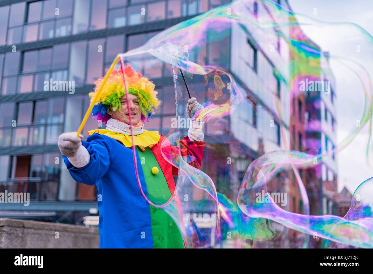 Gdansk,PL-16 Mar 22: Clown creating huge and bright soap bubbles in the air. Colorful clown providing entertainment for passing through people on the Stock Photo