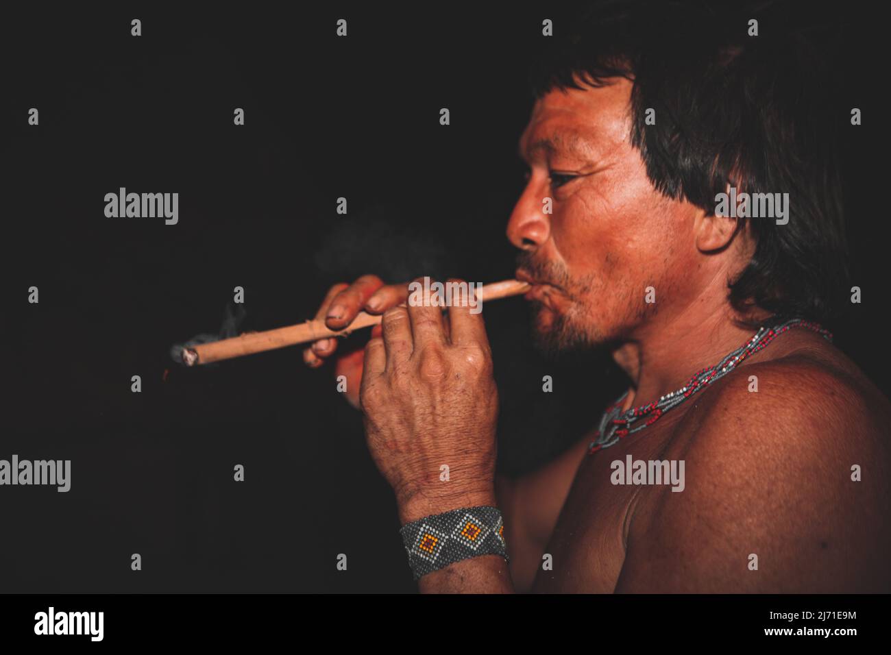 Asurini indigenous man smoking pipe during the night. Índio Brasileiro. Jogos Indígenas, Brazilian Amazon, 2010. Stock Photo