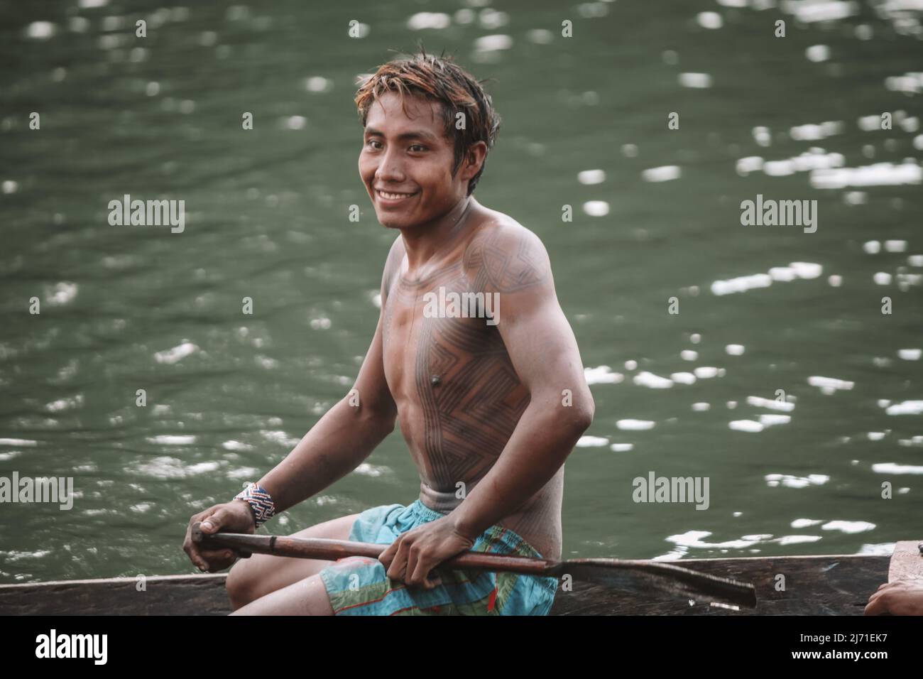 Indigenous caboclo man from an Amazon tribe in Brazil with tribal art painted on his body, riding canoe. Xingu River, Jogos Indígenas 2010. Stock Photo