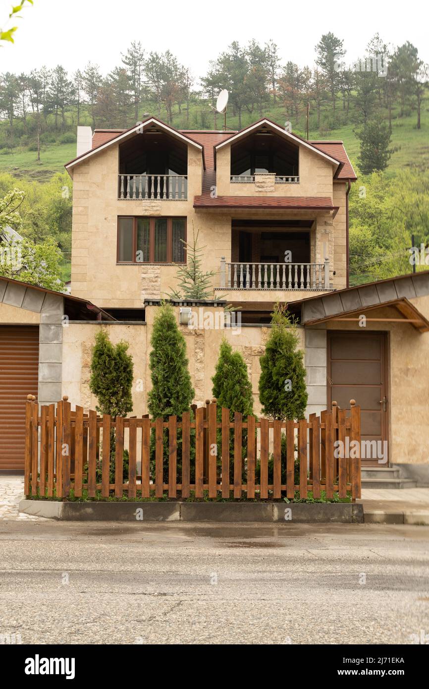 Dilijan, Armenia - May 5, 2022 - Yellow stone house with high front yard fence in Dilijan, Armenia Stock Photo