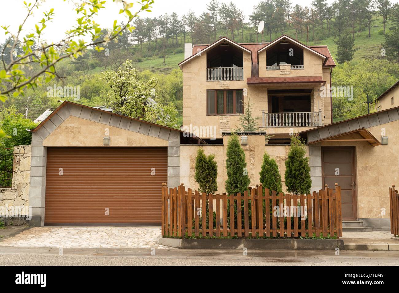 Dilijan, Armenia - May 5, 2022 - Clean and modern styel yellow stone house with high front yard fence in Dilijan, Armenia Stock Photo
