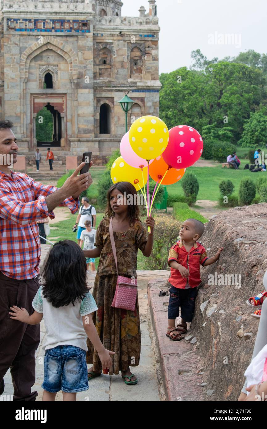 A dark Indian girl is trying to sell balloons, Concept - Child labor Stock Photo