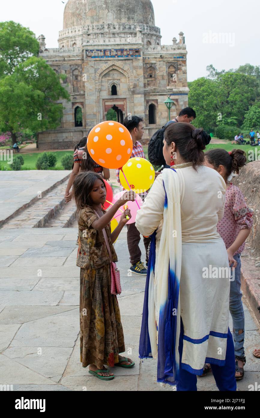 A dark Indian girl is trying to sell balloons, Concept - Child labor Stock Photo