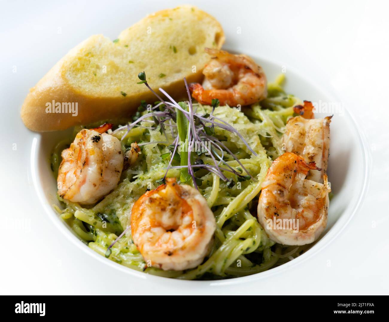 Spaghetti pesto topped with shrimps and and garlic bread Stock Photo